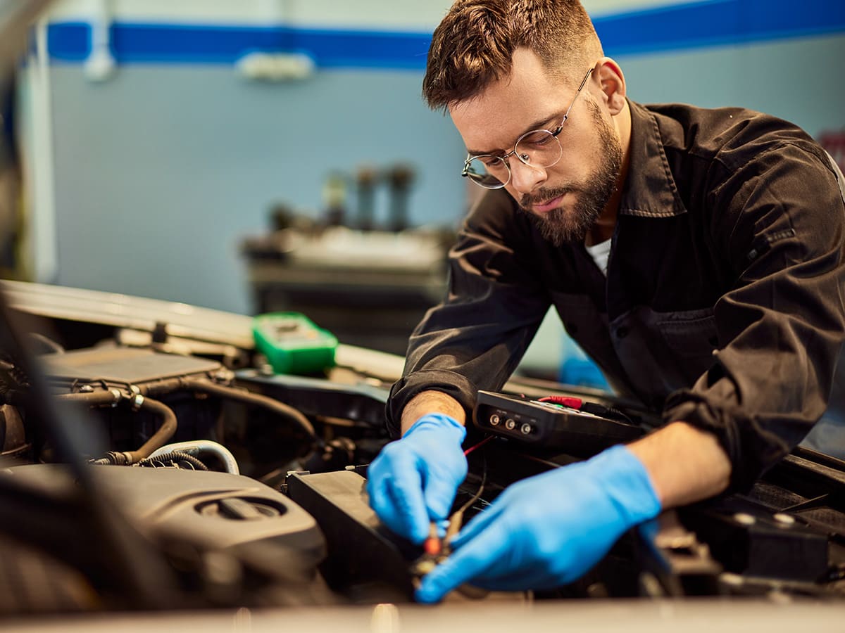 Service technician performing repairs in the engine bay of a vehicle.