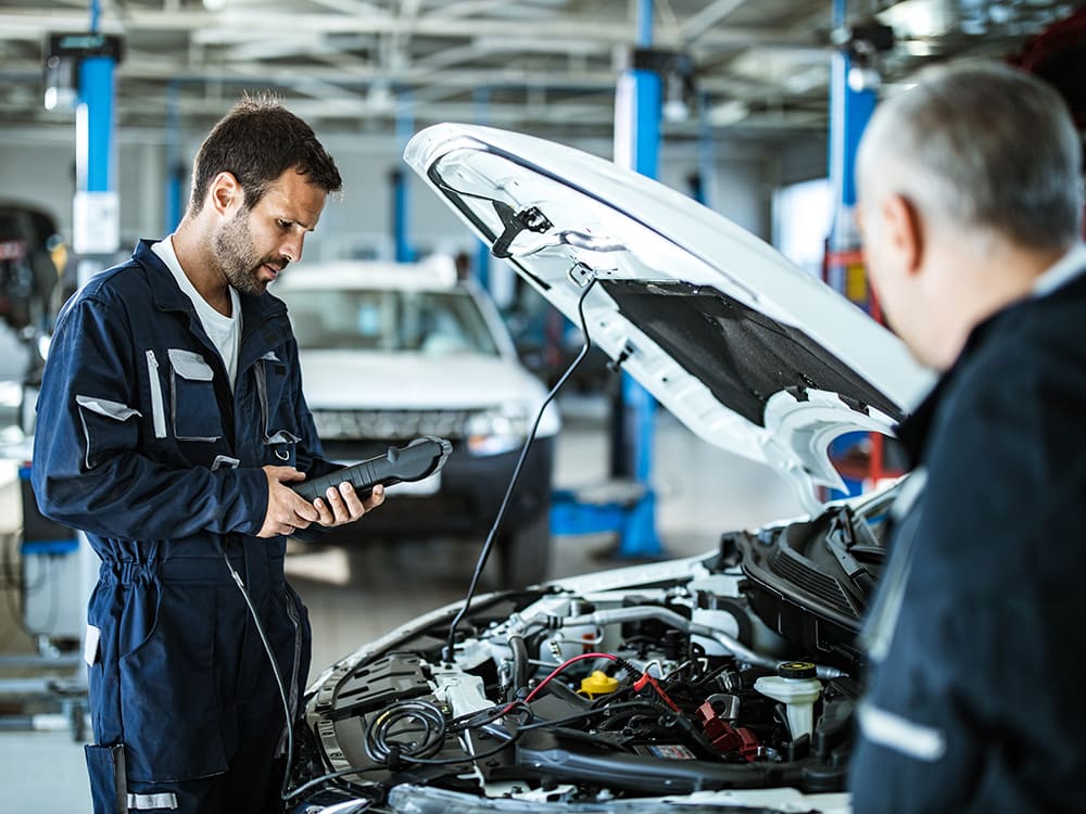 Ford service technician inspecting a vehicle in the service bay.